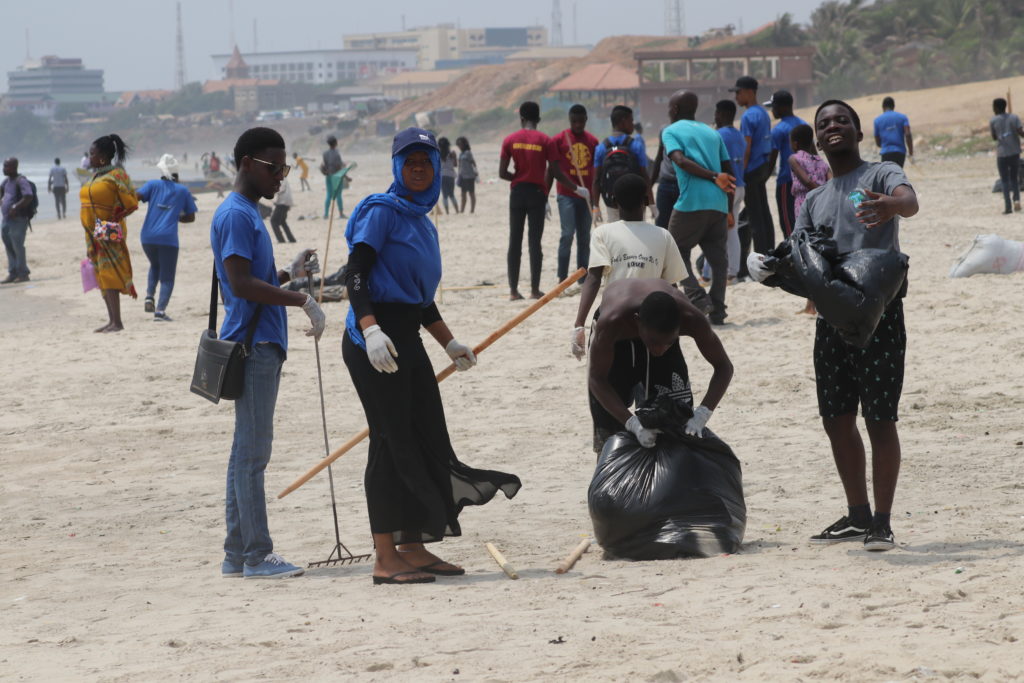 A group of young people with rakes, cleaning up beach in Accra, Ghana
