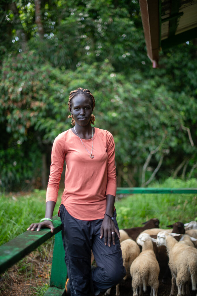 Apat Bul Kiir Aguer standing outdoors with sheep in the background